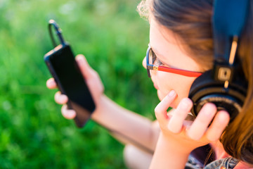 Teen girl listening to music with her retro  headphones outdoor