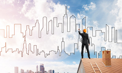 Man architect draw silhouette of modern city on blue sky. Mixed media