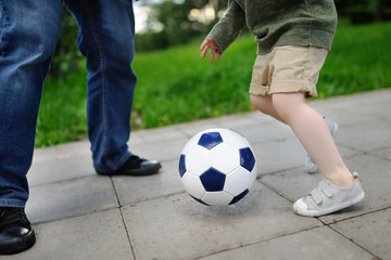 Little boy with his father having fun playing a soccer game on sunny summer day