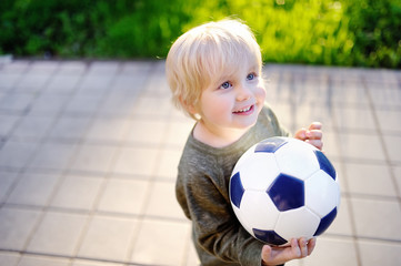 Fototapeta premium Little boy having fun playing a soccer game on sunny summer day