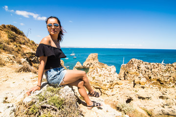 Latin Girl sitting on a cliff and enjoy the summer time near Atlantic ocean in Portugal