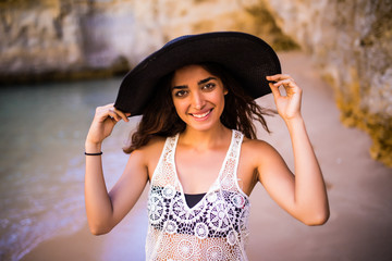 Beautiful latin girl wear in hat posing on the beach near ocean on summer vocation