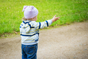 Child on road looks and shows his hand forward