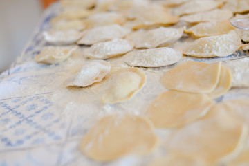 Fototapeta na wymiar Making dumplings, ravioli busy kitchen table background, closeup top side view