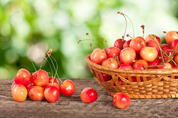 Yellow cherry in a wicker basket on a wooden table with a blurry garden background