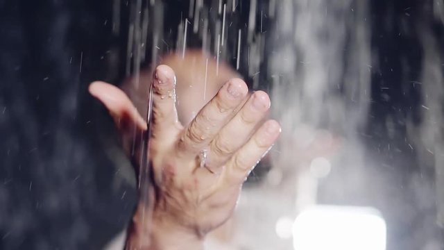 men's strong hand in meditation catches drops of water on the palm. the jets are split and travel along the sides of the spray