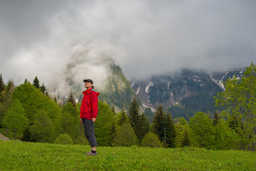Proud woman traveler stands on the alpine meadow