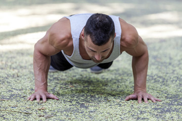 Obraz premium Picture of a young sportsman doing push ups outdoors