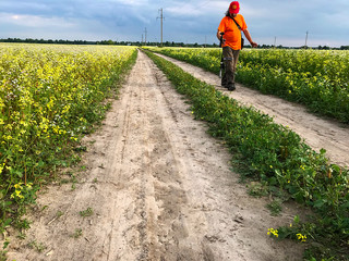 The tourist with the camera walks along the country road to the field and takes pictures.