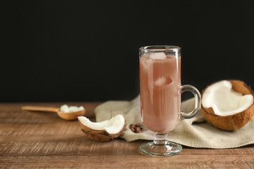 Glass of cold tasty coconut coffee on black background