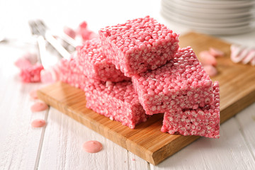 Cutting board with delicious rice treats and sweets on white table