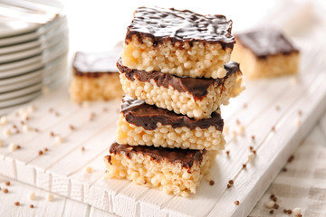 Delicious rice crispy treats with chocolate on wooden board