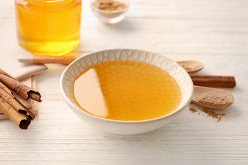 Bowl with honey and cinnamon on light table