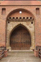 the large wooden gate of the old brick tower