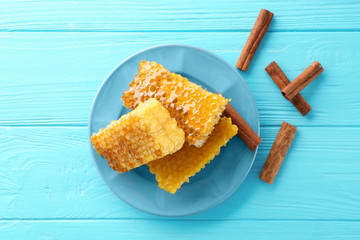 Plate with honeycombs and cinnamon on blue wooden table