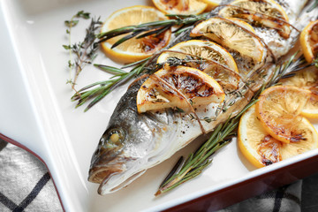 Baking dish with tasty fish, herbs and lemon