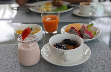 Healthy breakfast, nutrition concept: yogurt , fruits, nuts, fresh carrot juice, coffee. Balanced diet