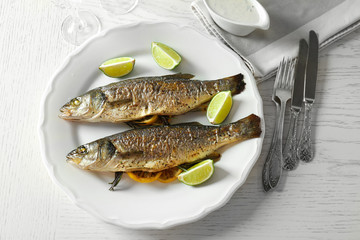 Two baked fish with lime and lemon on white plate