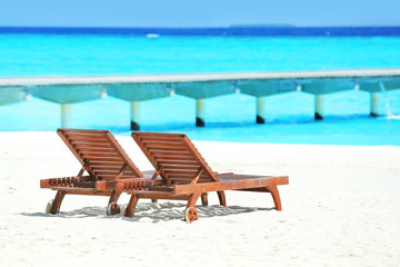 Wooden sun loungers on sea beach in summer day