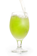 Green refreshing drink pouring into full glass. Isolated on white, clipping path included