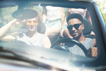 Young friends in cabriolet car ready to vacation