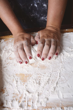 Close-up of woman hands kneading dough on wooden table. cooking and baking concept.