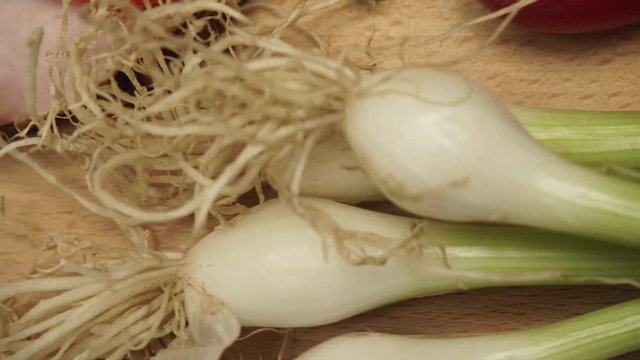 Close up of table wooden board with fresh food vegetables onion chive. Dolly sliding shot 4K ProRes HQ codec