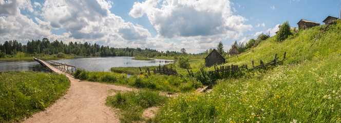 North Russian village. Summer day, river, old cottages on coast.