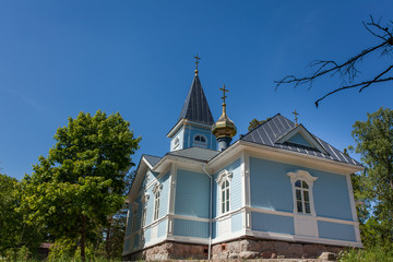 Fototapeta premium Blue church surrounded by forest on a sunny day