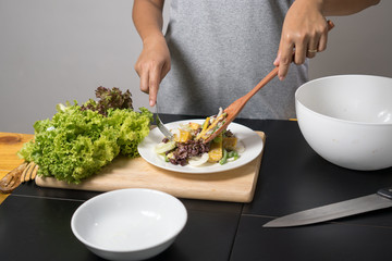 Woman mixing, cooking fresh salad and vegetable for making salad.