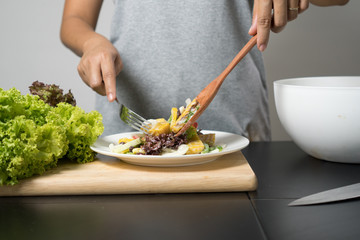 Woman mixing, cooking fresh salad and vegetable for making salad.