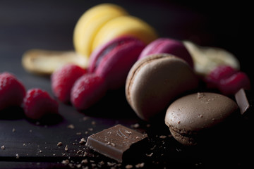 Group of colorful macarons with their ingredients over a wooden table