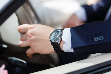 Hand man in an expensive blue suit driving a luxury convertible car. Businesswoman holding with one...