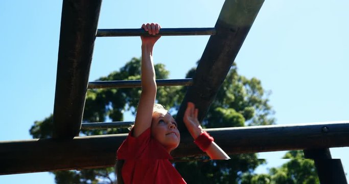 Girl climbing on monkey bar in the boot camp