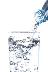 Pouring drinking water from bottle into glass on white background.