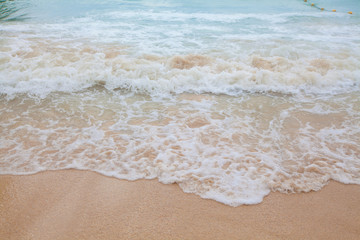 Abstract blurry background of soft wave of blue sea with sandy beach.