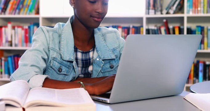 African American school girl using laptop in library
