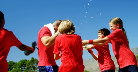 Kids splashing water on trainer in park