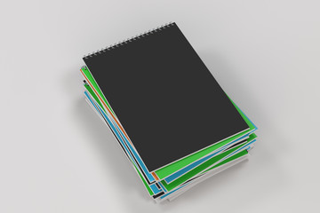 Stack of multicolored notebooks with metal spiral bound on white background