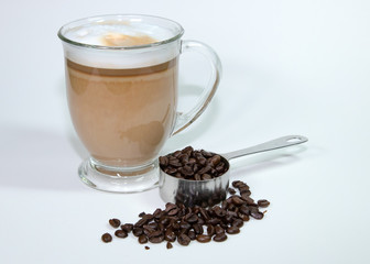 Latte in clear glass with coffee beans and scoop