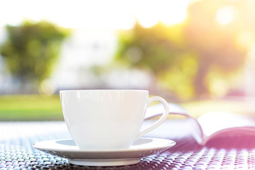 Coffee cup with book on blurred green nature background - chill out concept