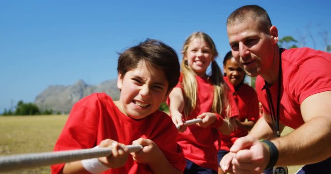 Trainer assisting kids in tug of war during obstacle course training
