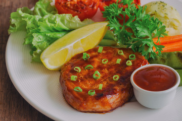 Barbecue pork steak on white plate served with barbecue sauce and vegetables. Pork steak for lunch or dinner on wood table. Moist and soft homemade pork barbecue served with mash potato and vegetable.