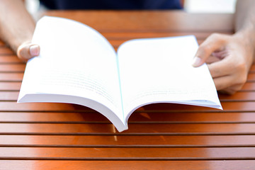 Hands opening book on the table - reading concept