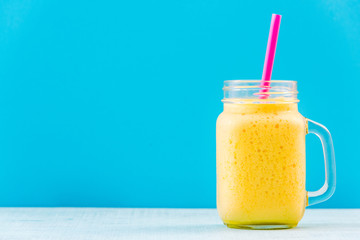 Mason jar with tropical smoothie on vibrant background