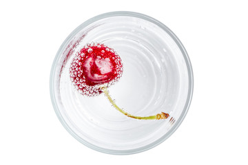 Ripe and sweet cherry in a glass of sparkling soda water placed on white background, healthy drinking concept.