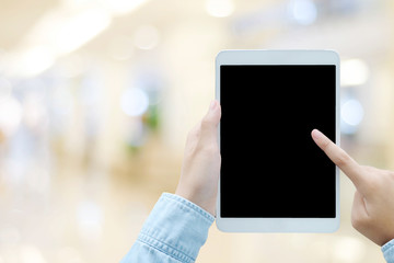 Hand using tablet with blank screen for mock up over blur store background, business and technology concept