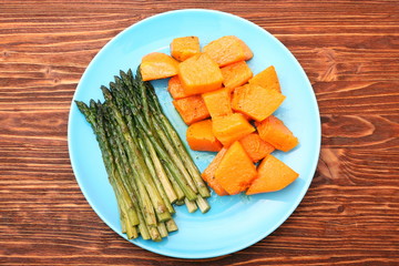 Baked asparagus pumpkin on plate on wooden background