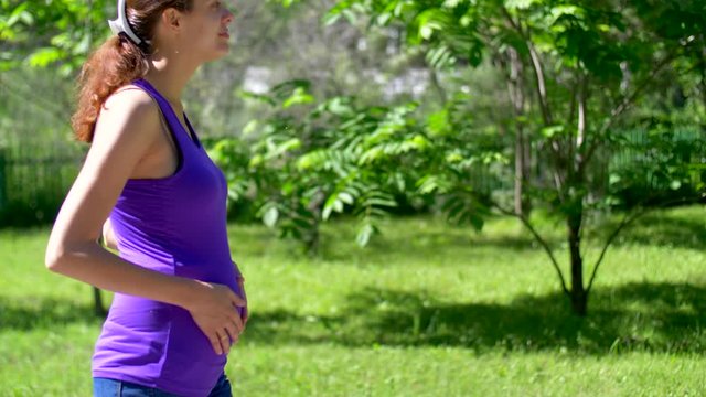 A pregnant girl walks through the forest