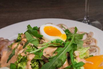 Salad with egg and mushrooms on a white plate and a wooden background